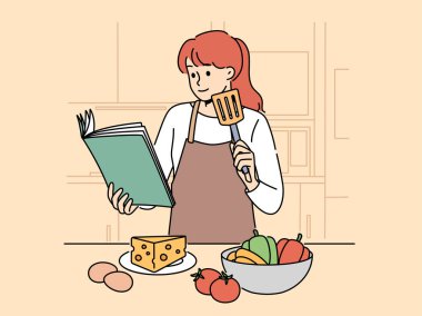 Yemek kitabı olan bir kadın mutfakta durup lezzetli yemekler, sebzeler ve yumurtalı peynirler pişirmek istiyor. Önlüklü kız, salata veya aperatif hazırlarken yemek kitabı kullanır.