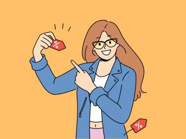 Mutlu kadın alışveriş ve kıyafet satın alma indirimlerini duyuruyor, yüzde sembolü olan etiketi işaret ediyor. Kız organizatör alışveriş merkezinde satışa davet etti ve Kara Cuma 'da büyük indirim sözü verdi.