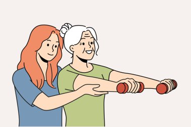 Yaşlı kadın fizyoterapistle antrenman yapıyor ve emeklilikten sonra sağlıklı kalmak için halterleri kaldırıyor. Fizyoterapist kız büyükannenin spor yapmasına yardım ediyor ve iyileşmek için spor yapıyor.