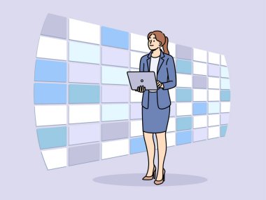 Telekomünikasyon şirketinde çalışan kadın izleme merkezinde duvar görüntüleriyle duruyor ve dizüstü bilgisayarını elinde tutuyor. Alan telekomünikasyon ve bilişim altyapı bakımı alanlarındaki yenilikleri kabul edin
