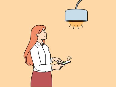 Işığı açmak için cep telefonu ya da akıllı ev uygulaması ile lambayı kontrol eden kadın. Kız akıllı telefona entegre olmuş modern iot teknolojilerini kullanmaktan ve hayatın rahatlığını artırmaktan hoşlanıyor
