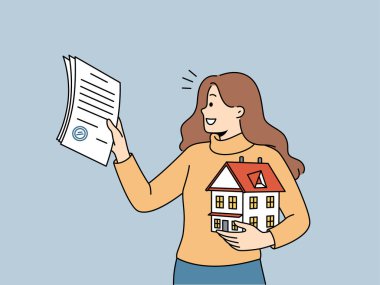 Kadın emlakçı insanlara emlak satın almalarında yardım ediyor ve ipotek sözleşmesini ve ev modelini elinde tutuyor. Emlakçı kız gülümser, ev satmaktan ve iş için yüzde almaktan memnun olur..