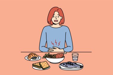 Sindirim problemleri yüzünden karın ağrısı çeken bir kız yemek masasında oturuyor. Hasta kadının mide ve sindirim organlarının sağlığını iyileştirmek için beslenme uzmanına ihtiyacı var..