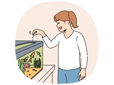 Küçük kız akvaryumda balık besliyor ve su altındaki evcil hayvanları zevkle yüzerken izliyor. Mutlu çocuk büyük bir akvaryumun yanında duruyor ve alglerin arasında yüzen deniz hayvanlarına yiyecek ikram ediyor.