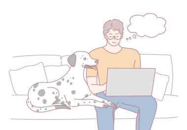 Dost canlısı bir Dalmaçyalı onun yanında otururken bir adam laptopunu rahatça kullanır.