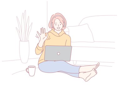 Genç bir kadın, sıcak ve rahat bir atmosferle çevrili dizüstü bilgisayarında mutlu bir şekilde çalışıyor.