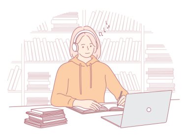 Bir öğrenci, kütüphanenin sıcak ve rahat atmosferinde dizüstü bilgisayarda çalışırken müzik dinlemekten zevk alır.