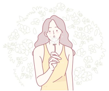 Sarı kolsuz tişörtlü bir kadının sakin bir tasviri, canlı bir çiçekli arka planda, düşüncelere dalmış.