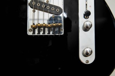 Klasik bir Amerikan elektro gitarının detayları. Krom ve akçaağaç yakalı siyah bir gitar.