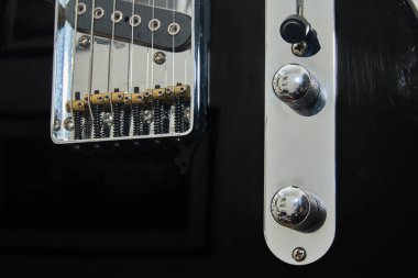 Klasik bir Amerikan elektro gitarının detayları. Krom ve akçaağaç yakalı siyah bir gitar.