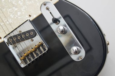 Klasik bir Amerikan elektro gitarının detayları. Krom ve akçaağaç yakalı siyah bir gitar.