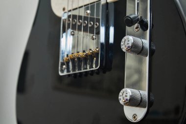 Klasik bir Amerikan elektro gitarının detayları. Krom ve akçaağaç yakalı siyah bir gitar.
