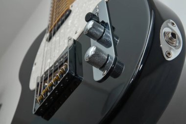 Klasik bir Amerikan elektro gitarının detayları. Krom ve akçaağaç yakalı siyah bir gitar.