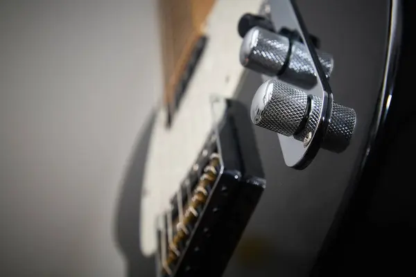 Klasik bir Amerikan elektro gitarının detayları, siyah, krom ve akçaağaç yakalı.