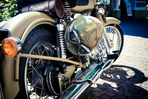 Özel yapım bir motosikletin profil fotoğrafı, krom rengi ve çamur gözlüklü askeri tarzda bir motosiklet kaskı.