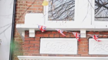 Londra, İngiltere - 2022.12.02: Batı Londra 'da bir evin penceresinden sallanan Union Jack bayrağının yavaş çekim görüntüleri
