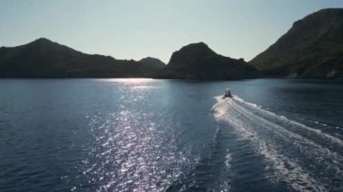 Yunanistan 'ın Corfu adası - 2023.07.01 - 09: Yunan adalarının sakin denizinin çarpıcı turkuaz sularında küçük bir motorlu tekne seyahat ediyor