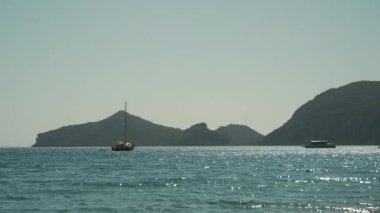 Korfu adası, Yunanistan - 2023.07.01 - 09: Sıcak bir günde plajdan çok da uzakta olmayan, güneşli denizde sallanan teknelerin videosu