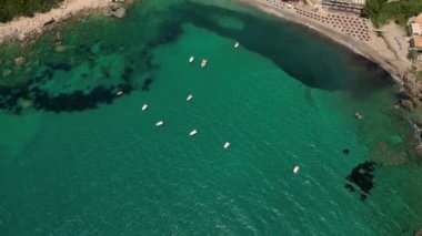 Korfu Adası, Yunanistan - 2023.07.01 - 09: Sıcak bir günde Paralia Ermones Sahili 'ne yakın bir yerde demirlemiş, güneşli denizde salınan teknelerin insansız hava aracı görüntüleri
