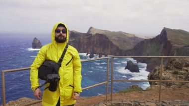 Madeira, Portekiz - 2023.04.04 - 09: Sarı yağmurluk giyen bir adam rüzgarlı bir günde Miradouro da Ponta do Rosto 'da duruyor