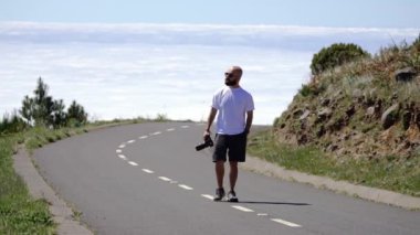 Madeira, Portekiz - 2023.04.04 - 09: Elinde kamera olan sakallı bir adam Madeira 'da boş yoldan yukarı çıkıyor