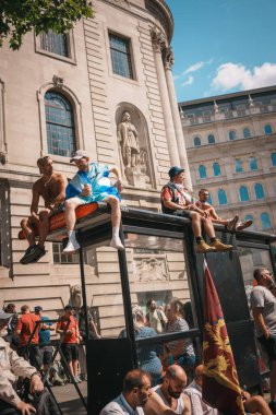 Trafalgar Meydanı, Londra - İngiltere - 2024.07.27: İngiliz bayraklı insanlar Özgürlük Yürüyüşü, İngiltere Yürüyüşü 'nde otobüs durağının tepesinde oturuyorlar 