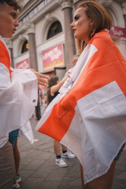 Euro Finalleri - Londra - İngiltere - 2024.07.14: Euro Finalleri sırasında İngiltere bayraklarına sarılmış şenlikli futbol taraftarları Londra 'nın merkezinde yürüyor. Canlı atmosfer, spor etkinliğinin heyecanını yakalıyor..
