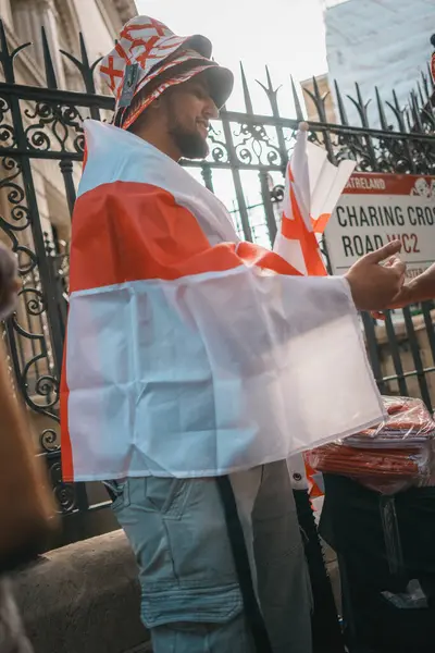 stock image Euro Finals - London - UK - 2024.07.14: Festive football fans wrapped in England flags walk through Central London during the Euro Finals. The lively atmosphere captures the excitement of the sporting event.