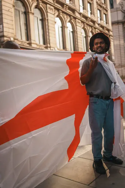 stock image Euro Finals - London - UK - 2024.07.14: Festive football fans wrapped in England flags walk through Central London during the Euro Finals. The lively atmosphere captures the excitement of the sporting event.