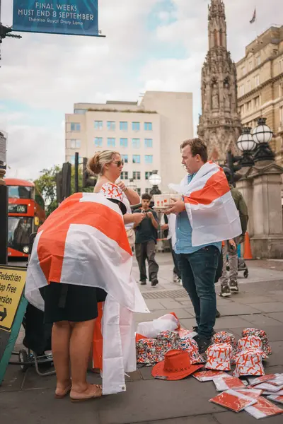 stock image Euro Finals - London - UK - 2024.07.14: Festive football fans wrapped in England flags walk through Central London during the Euro Finals. The lively atmosphere captures the excitement of the sporting event.