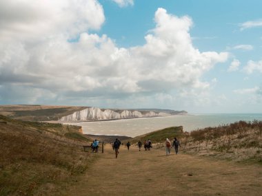 Seaford - Eastbourne - İngiltere - 2024.08.25 Seaford Sahili 'nde turistlerin kumlu ve çarpıcı mavi gökyüzünün tadını çıkardığı güneşli güzel bir gün. Yaz tatili ve kıyı tatili için mükemmel..