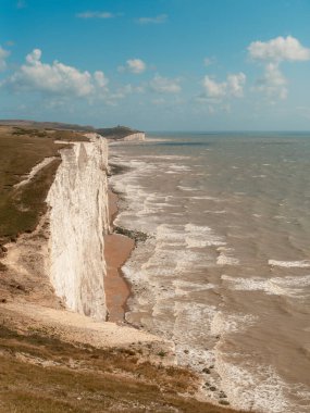 Seaford - Eastbourne - İngiltere - 2024.08.25 Seaford 'daki Seven Sisters uçurumlarının engin bir gökyüzünün altında okyanusta duran uzak deniz feneriyle dramatik manzarası.