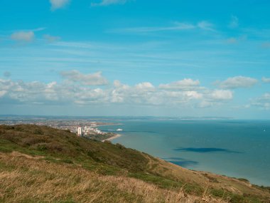 Seaford - Eastbourne - İngiltere - 2024.08.25: Güneşli mavi bir ufuk altında canlı manzara, deniz ve gökyüzünü gösteren bir tepeden Eastbourne kıyı kasabasının nefes kesici bir görüntüsü.
