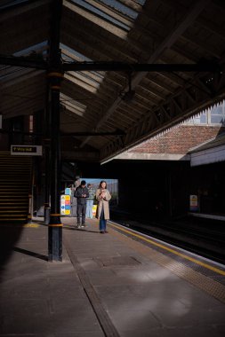İnsanlar güneşli kış gününde Boston Malikânesi Piccadilly metro istasyonunda tren bekliyor..