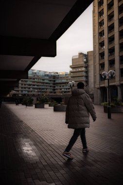  Barbican Mimarisi 'nin sokaklarında yürüyen bir adam