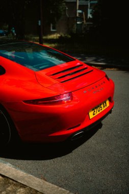 Chiswick London UK 2025.07.11 Viktorya tarzı kırmızı tuğla bir evin önünde park etmiş beyaz Morris Minor 'un koyu pencereli ve yeşil yapraklı görüntüsü.