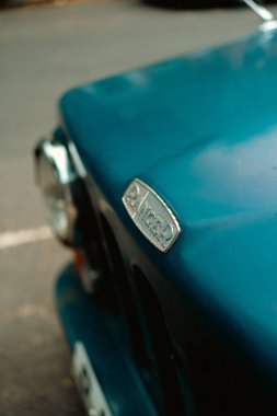 Chiswick, Londra, Birleşik Krallık 2025.07.09 Sakin bir Batı Londra caddesinde park edilmiş klasik mavi bir arabanın kaputuna takılmış eski bir gümüş Ranger rozeti. 