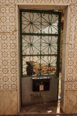 Algarve, Portekiz 2025.06.28 Pembe tişörtlü yaşlı bir adam Algarves 'in göbeğindeki mozaik kaplı bir alışveriş sokağının gölgesinde oturuyor.             