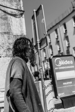 Algarve, Portekiz 2025.06.28 Pembe tişörtlü yaşlı bir adam Algarves 'in göbeğindeki mozaik kaplı bir alışveriş sokağının gölgesinde oturuyor.             