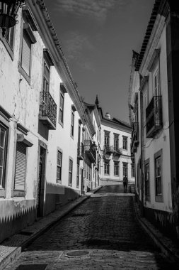 Algarve, Portekiz 2025.06.28 Pembe tişörtlü yaşlı bir adam Algarves 'in göbeğindeki mozaik kaplı bir alışveriş sokağının gölgesinde oturuyor.             