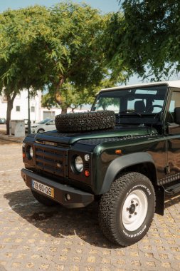 Algarve, Portekiz 2025.06.28 Pembe tişörtlü yaşlı bir adam Algarves 'in göbeğindeki mozaik kaplı bir alışveriş sokağının gölgesinde oturuyor.             