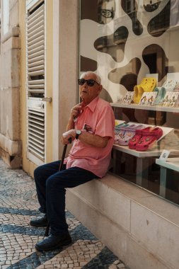 Tavira, Algarve, Portekiz 2025.07.02: Kemerli sütunlar, sallanan bayraklar ve güneşli ana meydanda çağdaş bir taş çeşme ile beyazlatılmış belediye binası                                                   