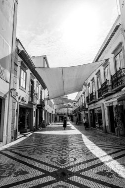 Tavira, Algarve, Portekiz 2025.07.02: Kemerli sütunlar, sallanan bayraklar ve güneşli ana meydanda çağdaş bir taş çeşme ile beyazlatılmış belediye binası                                                   