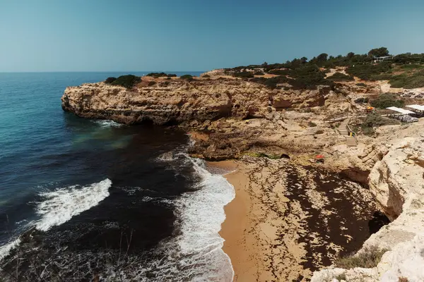 Tavira, Algarve, Portekiz 2025.07.02: Kemerli sütunlar, sallanan bayraklar ve güneşli ana meydanda çağdaş bir taş çeşme ile beyazlatılmış belediye binası                                                   