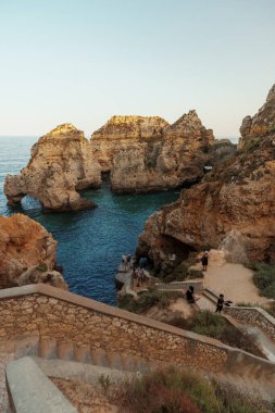 Tavira, Algarve, Portekiz 2025.07.02: Kemerli sütunlar, sallanan bayraklar ve güneşli ana meydanda çağdaş bir taş çeşme ile beyazlatılmış belediye binası                                                   