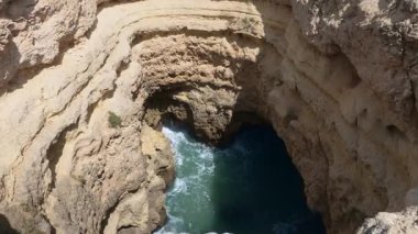 Algarve, Portekiz 2025.06.25 Doğal bir kaya oluşumu ve turkuaz dalgaların içeri çarptığı deniz mağarası, Algarve kıyı şeridi boyunca yukarıdan izleniyor.. 