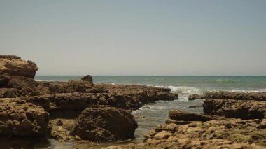 Portimo, Algarve, Portekiz 2025.07.01 Parlak yaz güneşi altında Praia dos Trs Castelos 'ta engebeli kaya oluşumlarına çarpan okyanus dalgaları. 