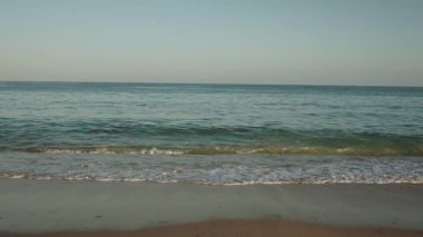 Algarve, Portekiz 2025.07.01 berrak bir gökyüzünün altındaki kumlu sahilde sakin dalgalar Atlantik Okyanusunun dingin güzelliğini yakalıyor.. 