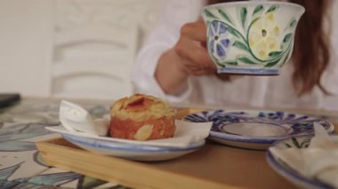 Algarve, Portekiz 2025.07.01 Bademli hamur işi ve kapuçino renkli bir el boyaması seramik bardakta servis edilir.. 