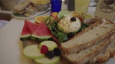 Portekiz 2025.07.01 Kahvaltı tabağı taze burrata peyniri, yabanmersini, karpuz, kivi, elma, zanaatkar ekmek ve beyaz bir masada çeşitli meyvelerle yakın plan. 